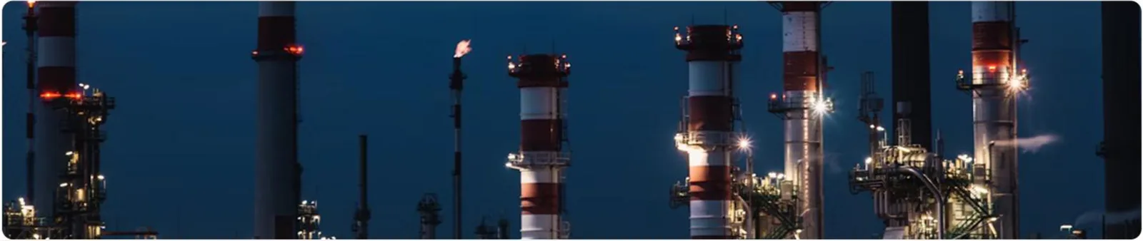 Chaminés de uma planta industrial iluminadas à noite