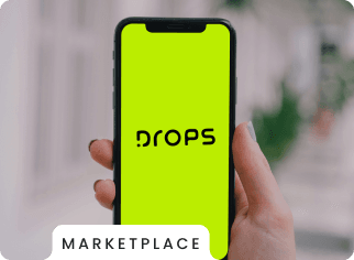 imagem de uma mão segurando um celular com a logo da drops no fundo de tela